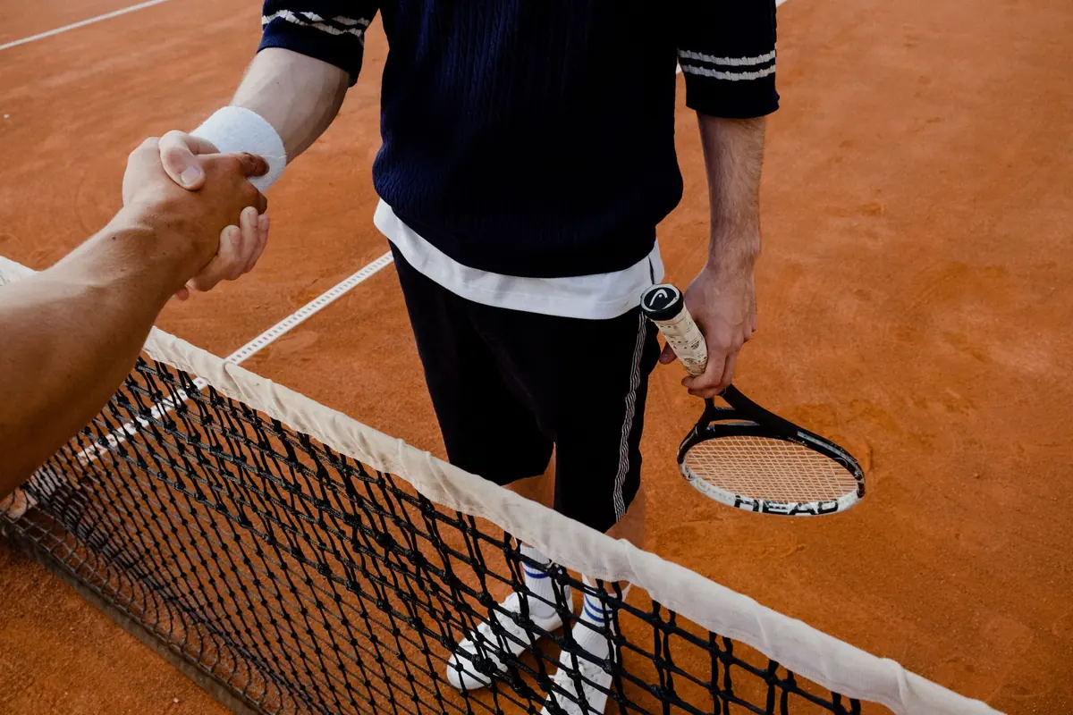 Tenis kortunda, fileyi aralarına alan iki oyuncu maç sonunda el sıkışıyor